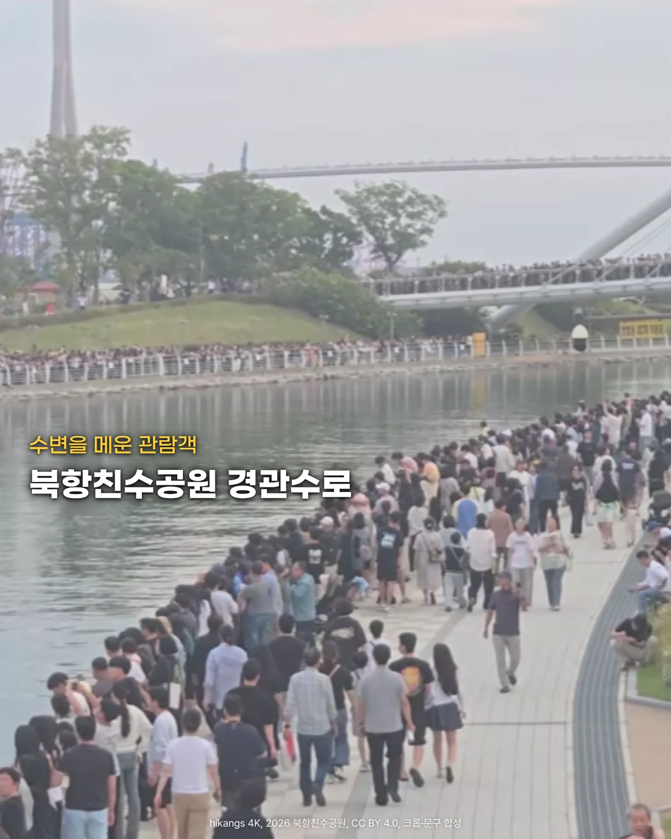 잔잔한 경관수로를 따라 오른쪽 수변 산책로에 관람객이 길게 줄지어 서 있고, 건너편 수변과 위쪽 아치형 보도교 위에도 사람들이 늘어서 있는 사진입니다. 왼쪽 아래 수면 위에 '수변을 메운 관람객'과 '북항친수공원 경관수로'라는 글자가 놓여 있습니다