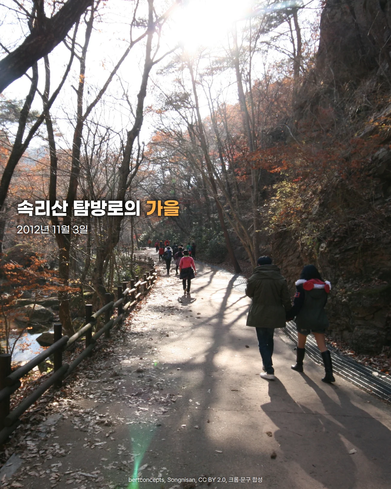 늦가을 햇빛이 역광으로 비치는 속리산 숲길 사진. 붉고 갈색으로 물든 나무 사이로 나무 난간이 이어진 포장 탐방로를 탐방객들이 걸어가고, 길 위에 낙엽과 긴 나무 그림자가 드리워져 있습니다. 왼쪽 위에 '속리산 탐방로의 가을' 문구와 촬영일 2012년 11월 3일이 있습니다
