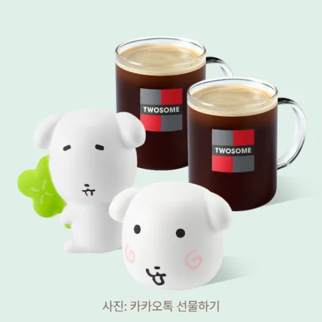 카카오톡 선물하기 상품 사진. 연한 민트색 바탕에 네잎클로버를 든 흰 가나디 스퀴시와 볼에 분홍 소용돌이 무늬가 있는 얼굴형 가나디 스퀴시가 앞에 놓이고, 뒤에 TWOSOME 로고가 찍힌 유리잔 아메리카노 두 잔이 있습니다.