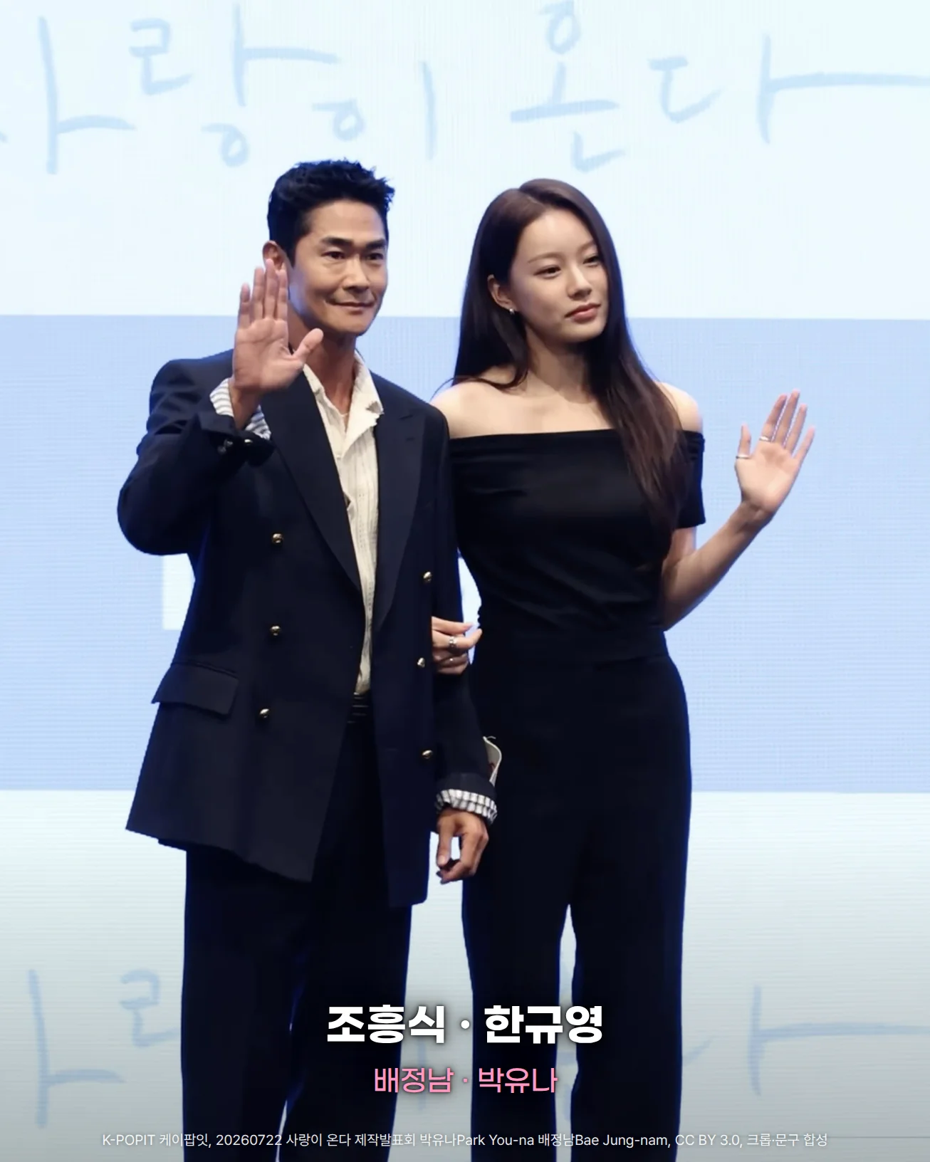 사랑이 온다 제작발표회 무대에서 '사랑이 온다' 글자가 있는 하늘색 배경 앞에 남색 정장을 입은 배정남과 검은 오프숄더 옷을 입은 박유나가 손을 흔드는 사진. 아래쪽에 '조흥식 · 한규영'과 '배정남 · 박유나' 문구가 있습니다.