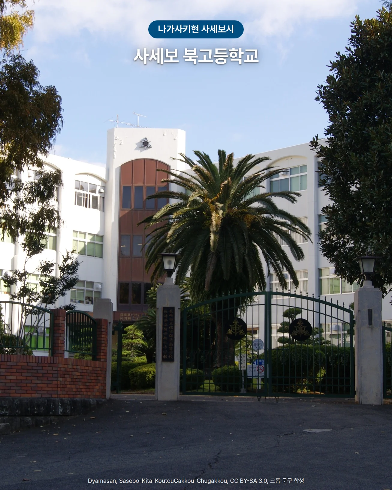 양옆의 큰 나무 사이로 붉은 벽돌 담과 초록 철문, 그 뒤 야자수와 흰 교사가 보이는 사세보 북고등학교 정문 사진. 위쪽에 '나가사키현 사세보시' 배지와 '사세보 북고등학교' 글자가 있습니다