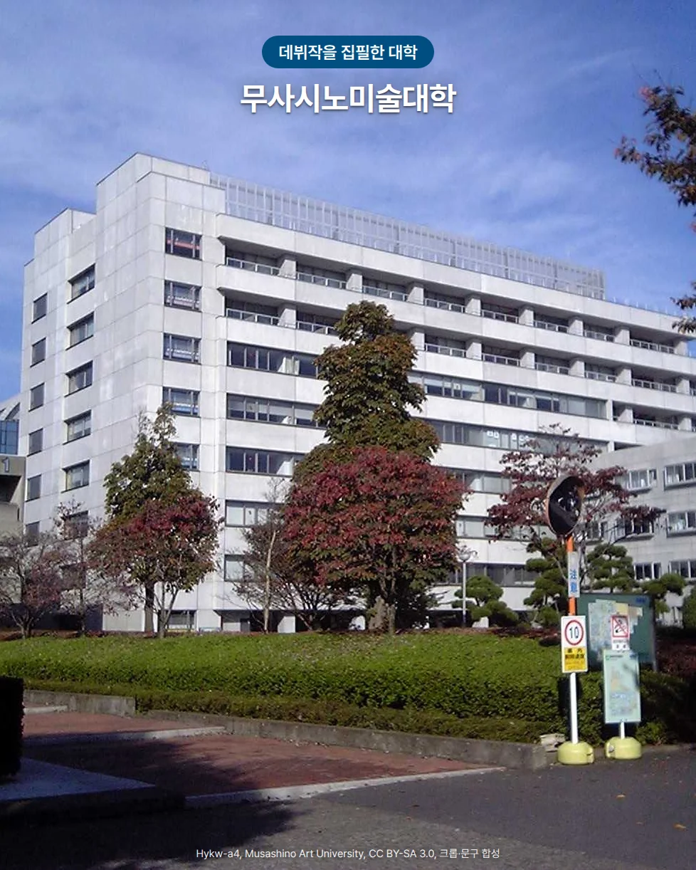 푸른 하늘 아래 붉게 물든 나무들 뒤로 흰 고층 건물이 선 무사시노미술대학 캠퍼스 사진. 위쪽에 '데뷔작을 집필한 대학' 배지와 '무사시노미술대학' 글자가 있습니다