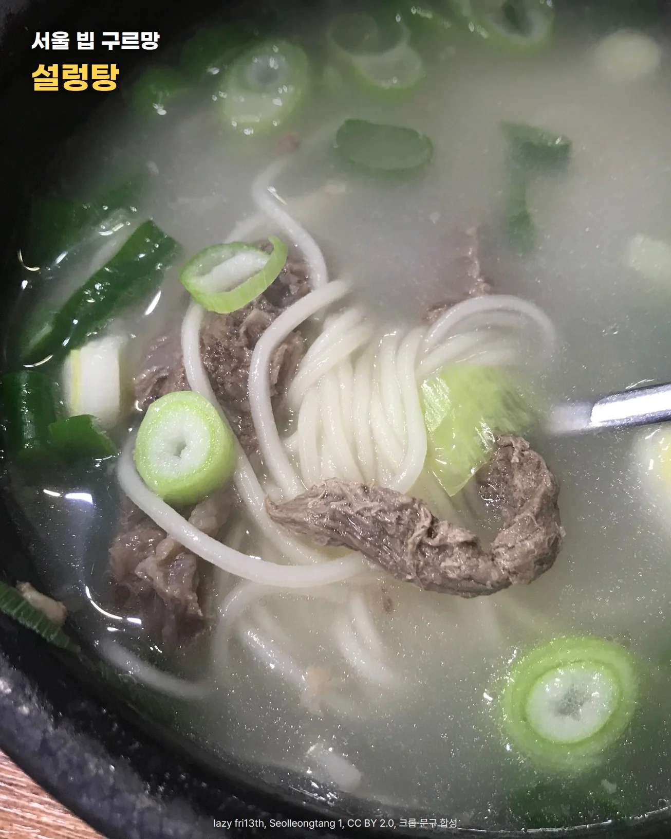 검은 뚝배기에 담긴 맑은 국물의 설렁탕을 위에서 가까이 본 사진. 소고기와 소면, 송송 썬 대파가 국물에 잠겨 있고 오른쪽에서 숟가락이 들어와 있다. 사진 위에 '서울 빕 구르망, 설렁탕' 문구