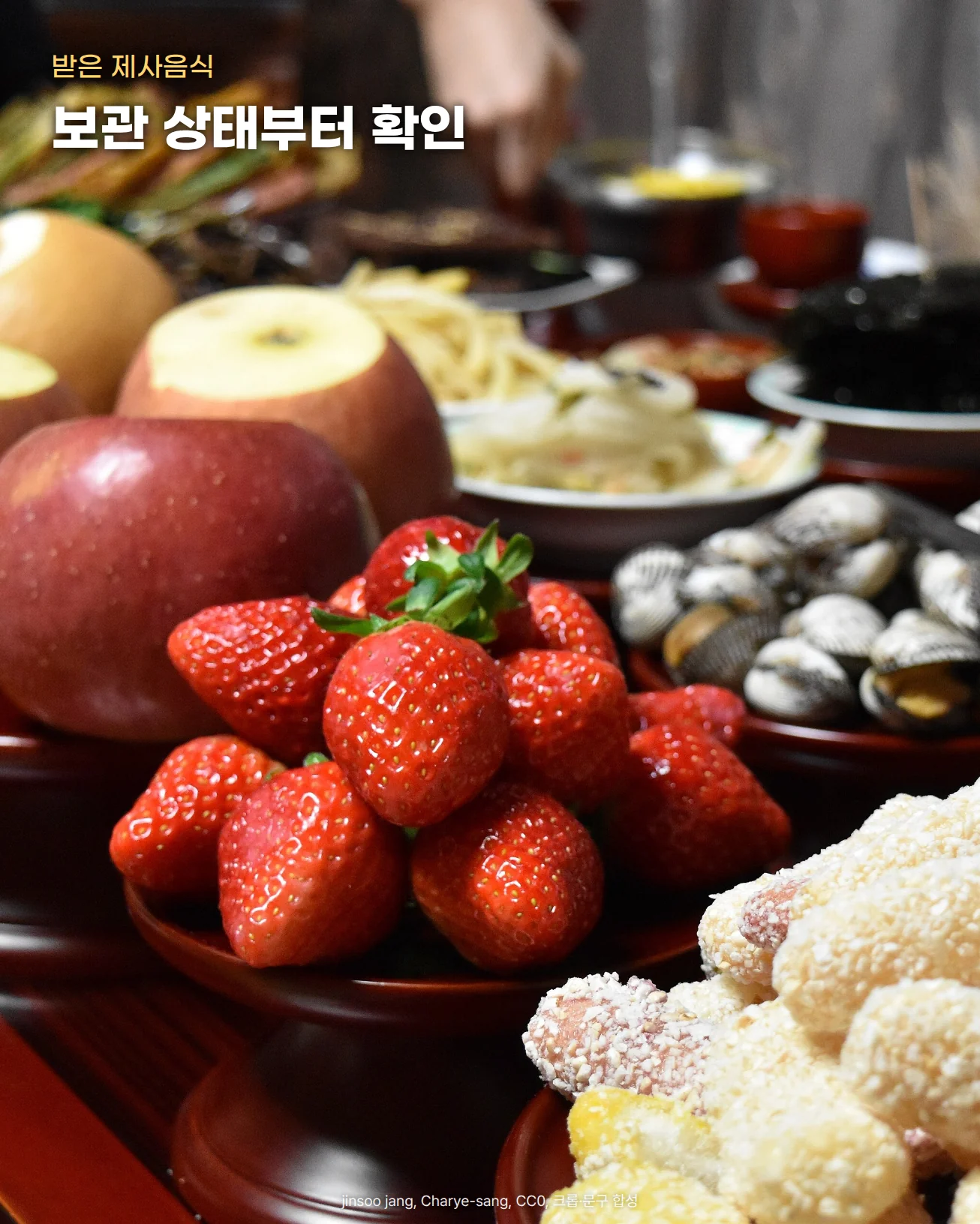 붉은 제기에 소복이 쌓은 딸기와 사과, 앞쪽 접시의 강정, 뒤편 조개와 구운 조기 접시를 가까이 찍은 차례상 사진. 위쪽에 '받은 제사음식'과 '보관 상태부터 확인' 글자를 넣었습니다.