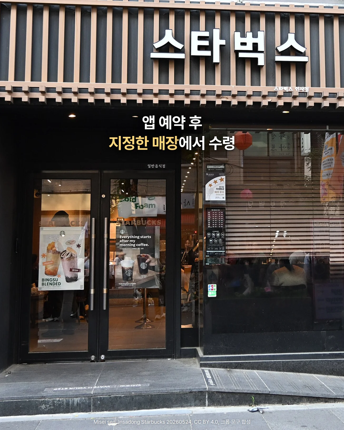나무 루버 파사드에 흰 한글 간판 '스타벅스'를 단 인사동 스타벅스 매장 외관과 유리 출입문 사진. 간판 아래 어두운 띠에 '앱 예약 후 지정한 매장에서 수령' 문구